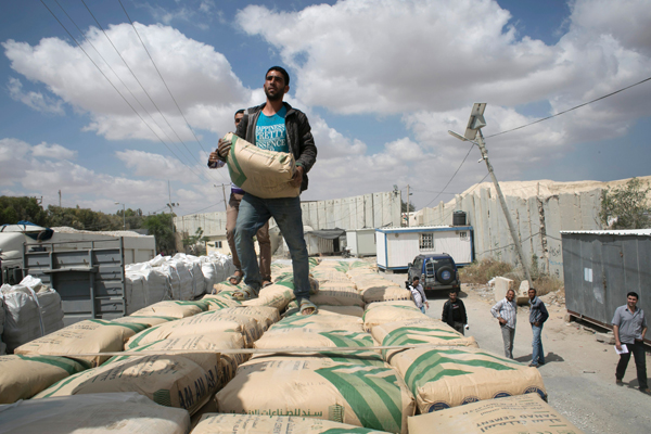 Palestinian workers stand on a truck carrying bags of cement after it entered the southern Gaza Strip from Israel through the Kerem Shalom crossing in Rafah on Monday (AFP photo)